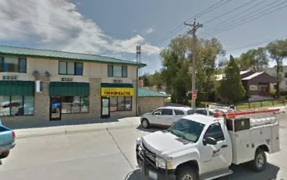 Small commercial building with storefronts and parked vehicles on a suburban street
